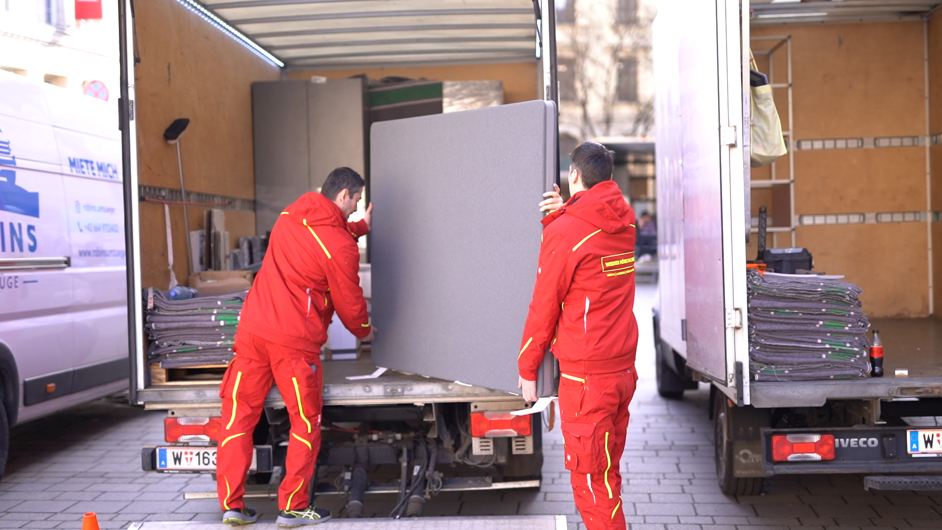 Wiener Möbelpacker tragen Schwerlast in einen Umzugstransporter